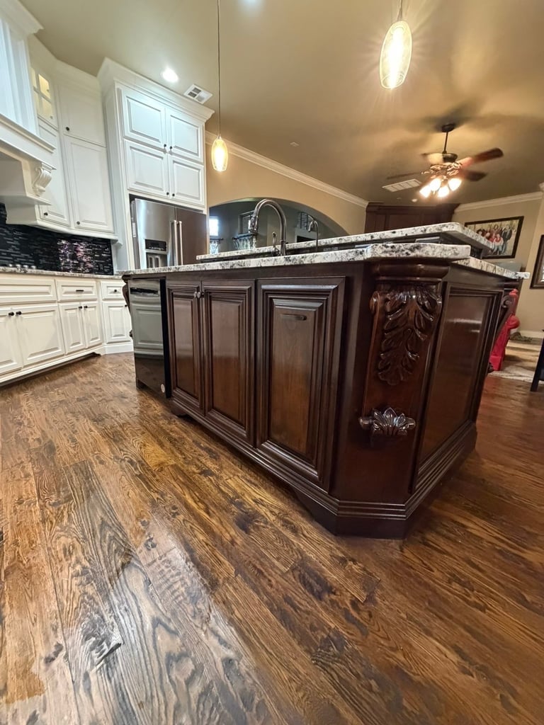 Modern kitchen with white cabinetry, dark wood island, granite countertop, and hardwood flooring
